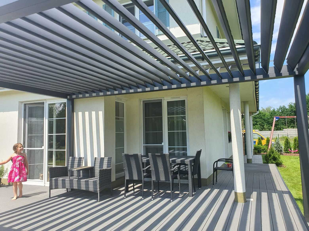 Pergola żaluzjowa na taras z otwartymi lamelami dachowymi zamontowana przy budynku – SuperPergole Warszawa