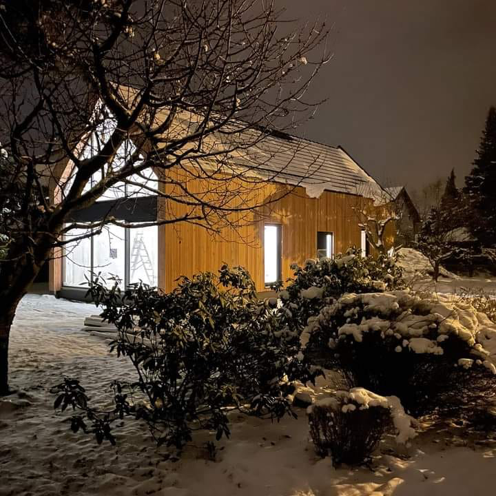 FuturaDom – ciepły, energooszczędny dom z drewna w Ruszczynie, oświetlona elewacja z desek w zimowej scenerii