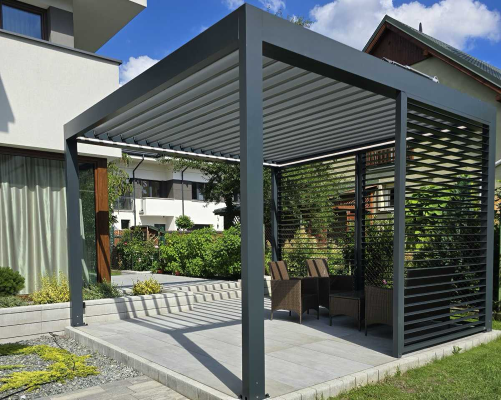 Nowoczesna pergola żaluzjowa tarasowa z aluminiowymi lamelami i boczną osłoną typu shutters stojąca w ogrodzie – SuperPergole Warszawa
