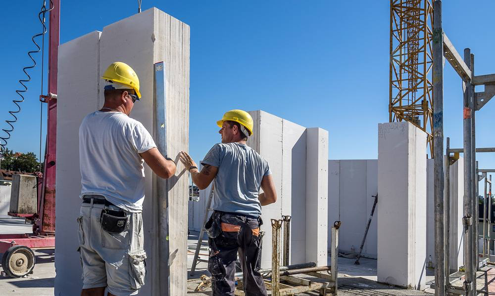Dwóch pracowników montuje na budowie panele Ytong Panel SWE Ultra plus przy użyciu sprzętu dźwigowego