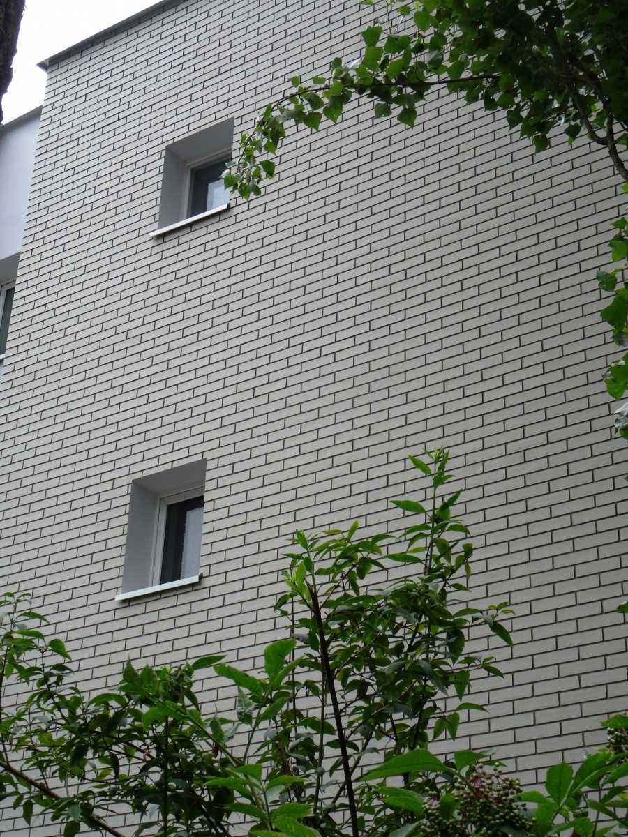 Imitacja białej cegły z szarą fugą na elewacji budynku, płytki elastyczne PromaDekor CE