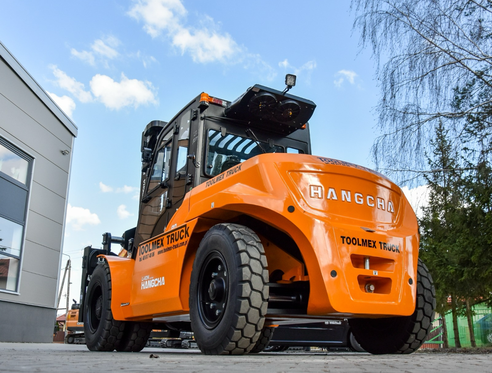 Pomarańczowy wózek widłowy Hangcha Toolmex Truck przed halą.