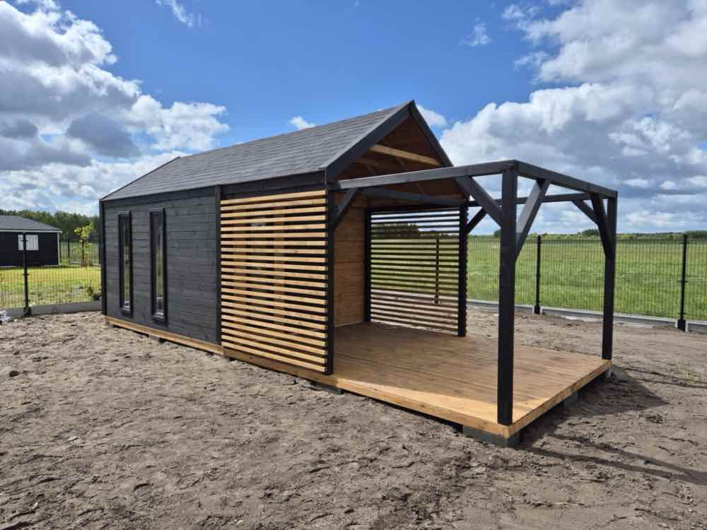 2. Nowoczesny domek narzędziowy z altaną i tarasem w kontrastowej czarno-drewnianej stylistyce.