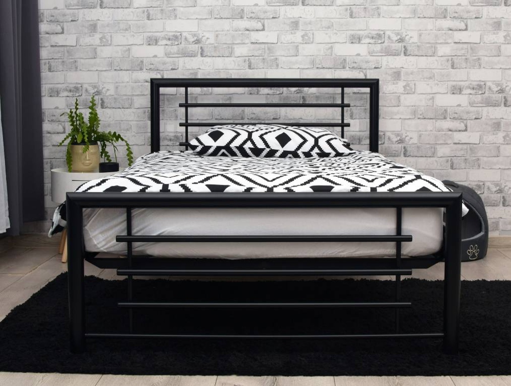 Metalowe łóżko w miedzianym kolorze na tle tapety w liście w nowoczesnej aranżacji sypialni.