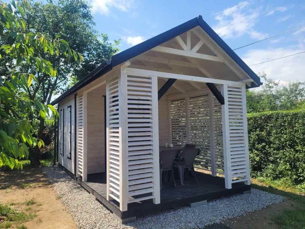 5. Ogrodowy domek narzędziowy z altaną i lekką, białą zabudową lamelową.