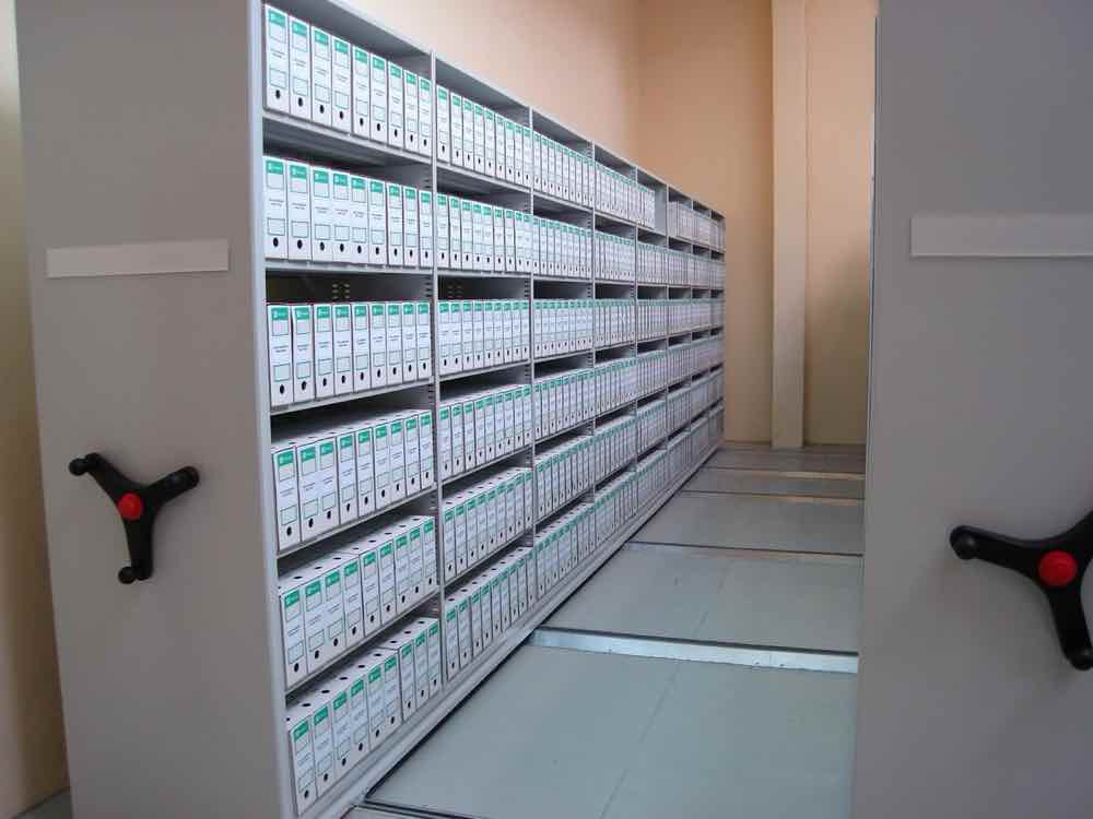 Regały przesuwne do archiwum z segregatorami, pokazujące oszczędność miejsca i uporządkowane przechowywanie dokumentacji