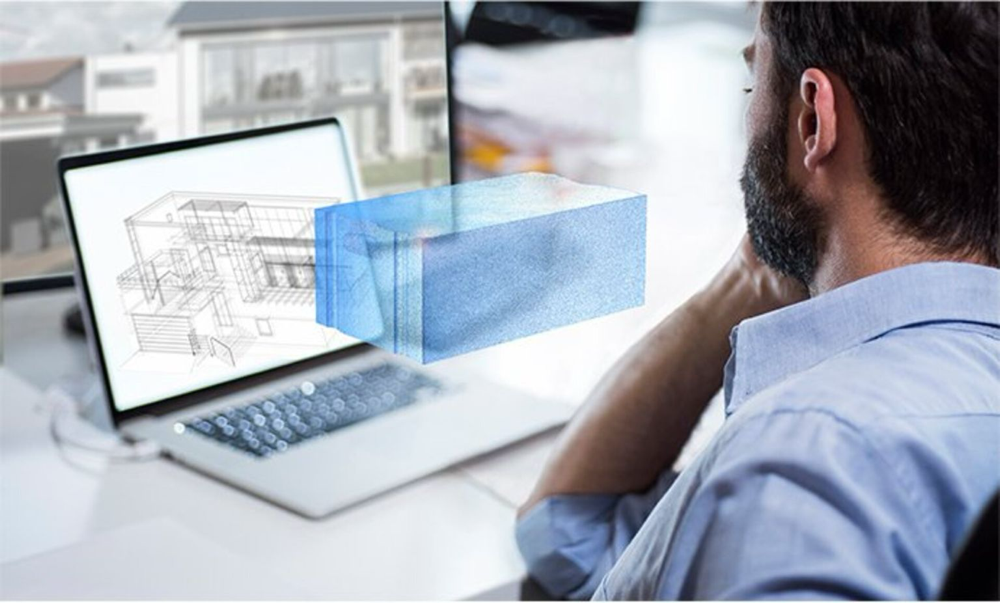9. Mężczyzna pracujący przy laptopie z modelem 3D budynku i wizualizacją bloczka z betonu komórkowego w technologii BIM.