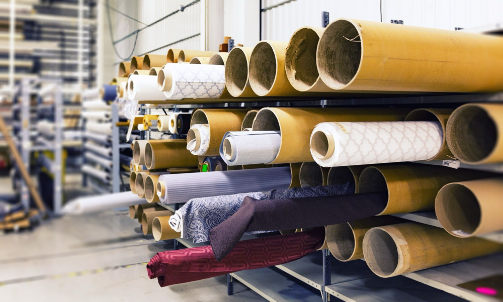 2. Tuleje tekturowe z nawiniętymi tkaninami przechowywane na regale w hali produkcyjnej.