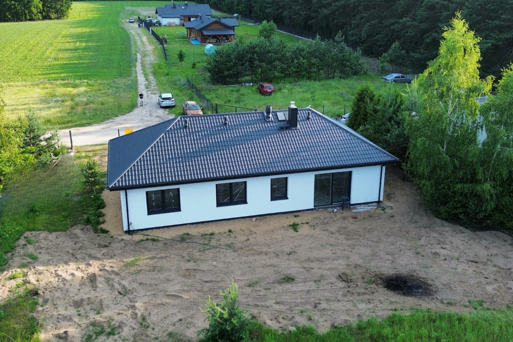 7. Gotowy dom z prefabrykatów FLiXHOME z białą elewacją i ciemnym dachem.