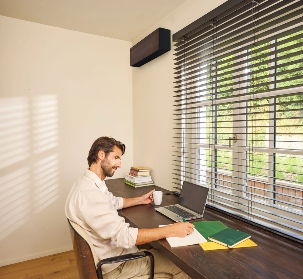 8. Klimatyzator Daikin Stylish w wykończeniu inspirowanym ciemnobrązową skórą w domowym gabinecie.