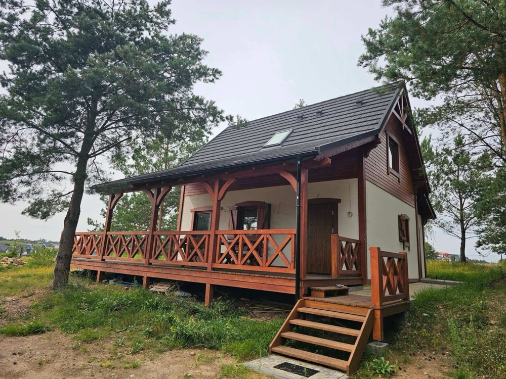 Dom drewniany KARKO z dużym zadaszonym tarasem i drewnianą balustradą.